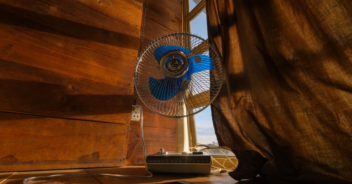 A nostalgic scene featuring an electric fan and cellphone by a sunlit curtain.